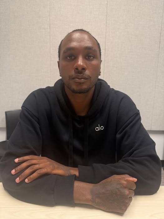 Front-facing man in a black hoodie with an 'alo' logo, seated at a table and looking at the camera.